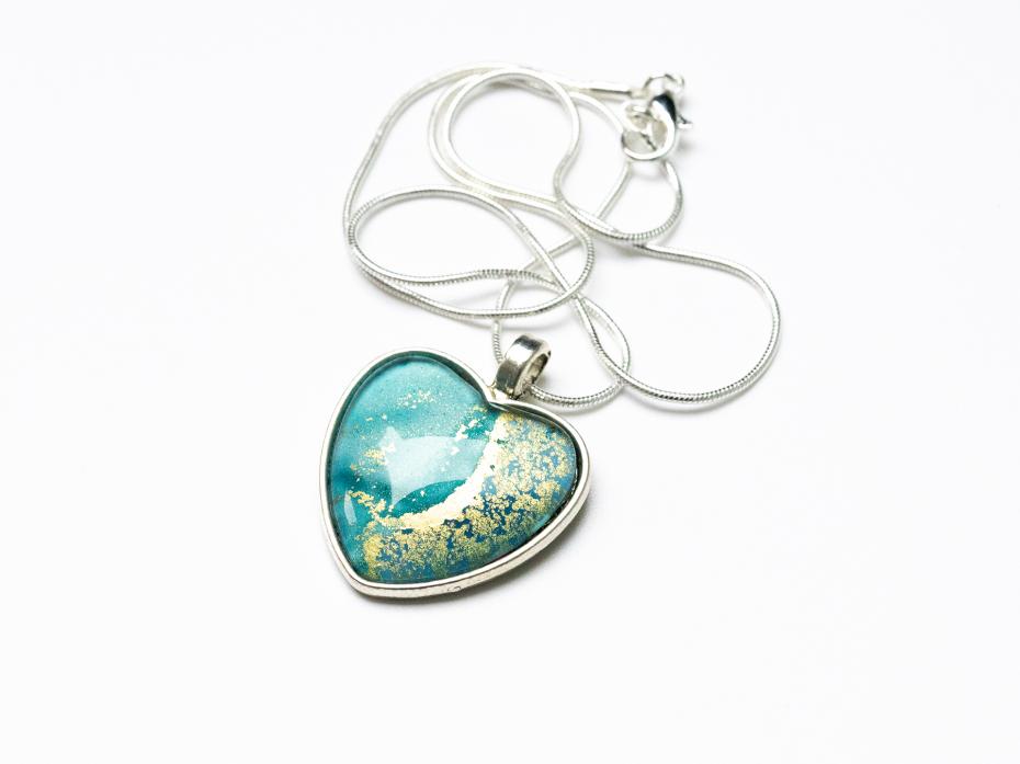 Turquoise and gold alcohol ink art placed in a heart shaped pendant